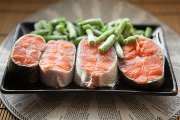 Salmon with frozen string beans on black plate