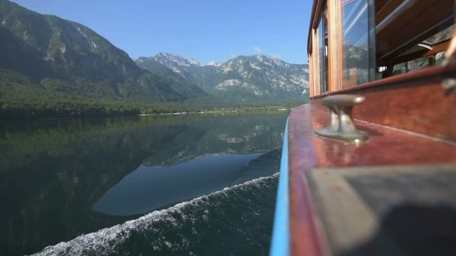 Tourist boat sailing on Bohinj lake in Slovenia, side view of the vessel with waves on water surface