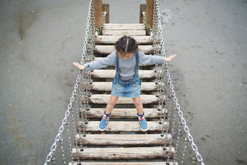 Little girl crossing suspension bridge