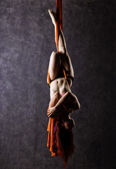 Beautiful sexy dancer on aerial silk, graceful contortion, acrobat performs a trick on a ribbons