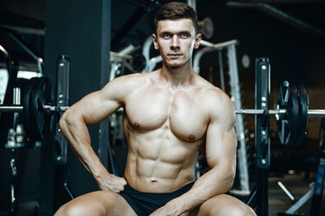 Naklejka na ściany i meble Handsome model young man working out in gym