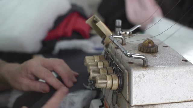 Tailoring close up, thread old sewing machine in focus, tailor stitching fabric textile in the blurred background, shallow depth of field, concept workshop, interior scene