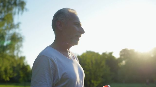 Delighetd aged man drinking water after running