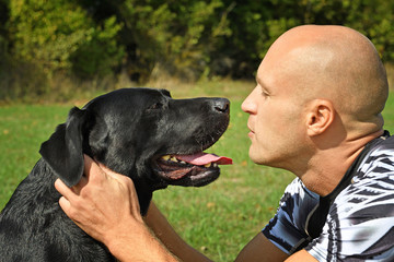 Man with black dog in the park at sunny day.