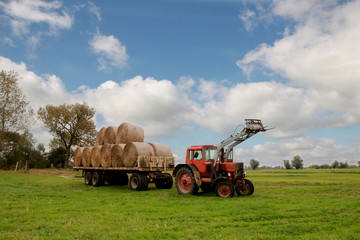roter traktor mit einer Ladung heuballen © Levtrona
