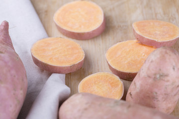 Raw sweet potato on wood background.