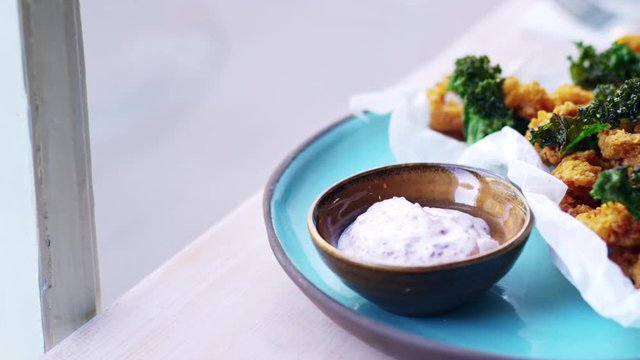 Fried squid, kale and sumac mayo by a window, close up pan