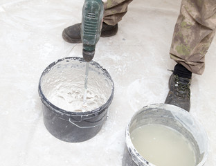Obraz premium Worker mixes the solution with white plaster