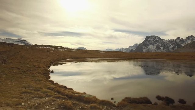 side POV walking on fall valley lake and snowy mounts approaching sunset.Sunny autumn day Hiking in colorful red forest wild nature mountain outdoors.Alps Devero.4k point of view establishing video