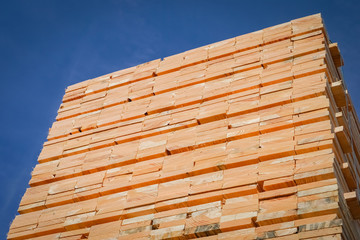 Holzindustrie - Bauholz, Stapel frisch geschnittener Bretter vor blauem Himmel