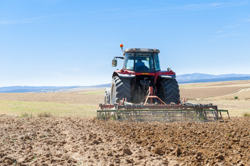 agricultural tractor in the foreground with blue sky background.