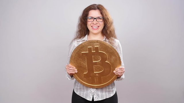 Happy woman showing big Bitcoin coin. Virtual money concept. Cryptocurrency