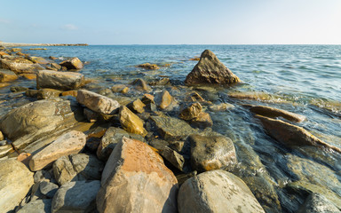 Sea waves lash line impact rock on the beach. Sunny backgrounds wallpaper.