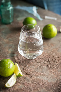 Glass of cold sparkling water and fresh limes on rustic backgrou