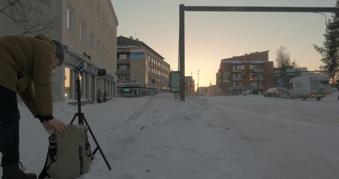 ROVANIEMI, FINLAND - JANUARY 06, 2017: Man stocker (with model release) fixing tripod with seven Go Pro cameras to shot 360 VR video of winter city streets st sunset