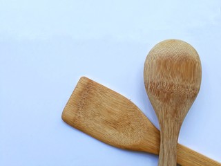 Closeup top view wooden spade of frying pan and ladle on white background.