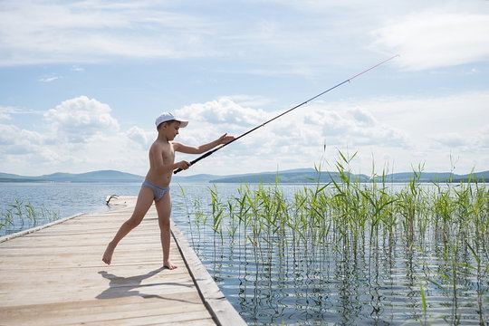 Маленький мальчик ловит рыбу на удочку