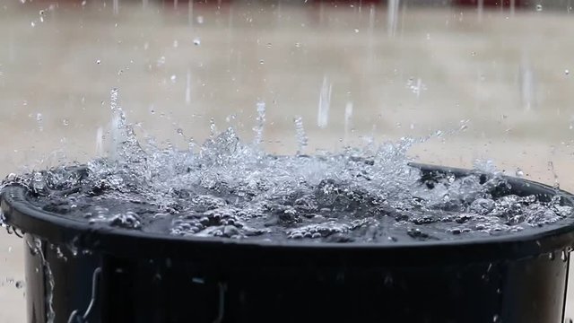 Raining water falling in full bucket, Rain is liquid water in form of droplets that have condensed from atmospheric water vapor.
