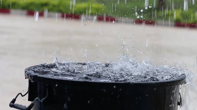Raining water falling in full bucket, Rain is liquid water in form of droplets that have condensed from atmospheric water vapor.