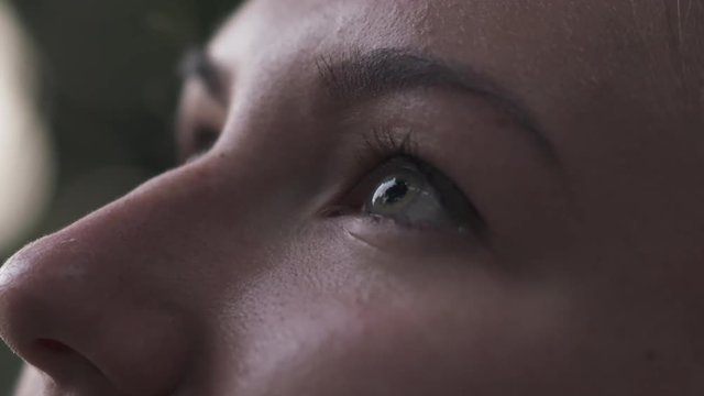 Slow motion handheld closeup teenage girl with green eyes look up on town street in shade
