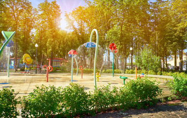 Water fountains on the playground in the park. The sun shines brightly.