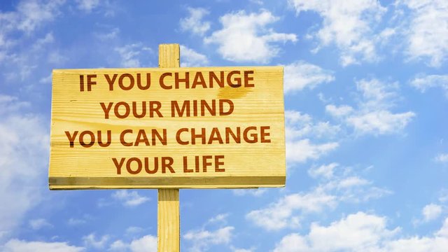 If you change your mind you can change your life. Words on a wooden sign against time lapse clouds in the blue sky.