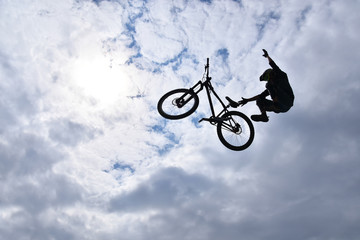 Fototapeta na wymiar Dark silhouette of freestyle stunt cyclist flying in the sky