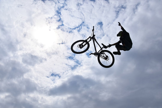 Dark Silhouette Of Freestyle Stunt Cyclist Flying In The Sky