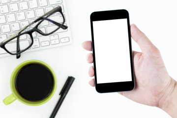 Man is holding a black smartphone with white blank mockup screen over the white desk table.