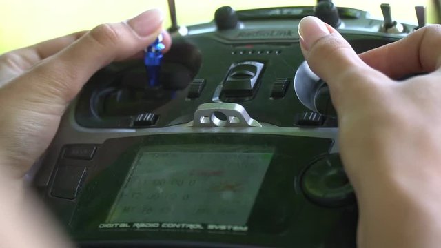 Female hands move the joysticks on the remote contol of the drone, below the display with the characteristics of the flight of the drone