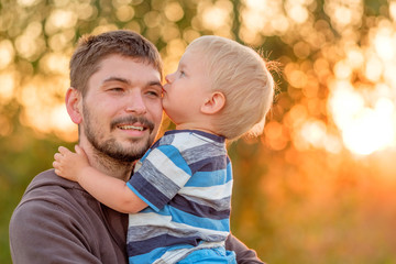 Father and son outdoor portrait in sunset sunlight