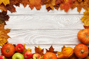 Naklejka na ściany i meble Autumn leaves, apples and pumpkins over wooden background
