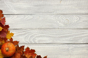 Autumn leaves and pumpkin over old wooden background