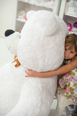 Little girl hugs a big teddy bear. A toy is a Christmas present.