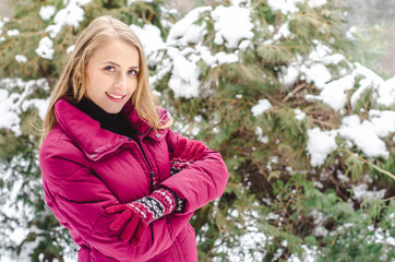 young smiling fashionable woman wearing in winter clothes smiles at the camera on the background of winter nature.