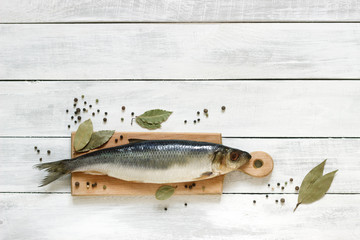 Herring with spices on a wooden board. The background. Rustic style, selective focus.