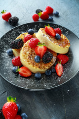 British Crumpets breakfast with blueberries, strawberries, blackberries, raspberries drizzled with icing sugar