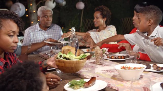 Multi generation black family serving food at table outdoors