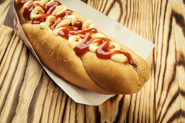 Barbecue Grilled Hot Dog with sauce,Hot Dog With Yellow Mustard,Onion,Pickles and French Fries,Tasty hot-dogs with vegetables on wooden background, close up,hot dogs with mustard, ketchup and relish