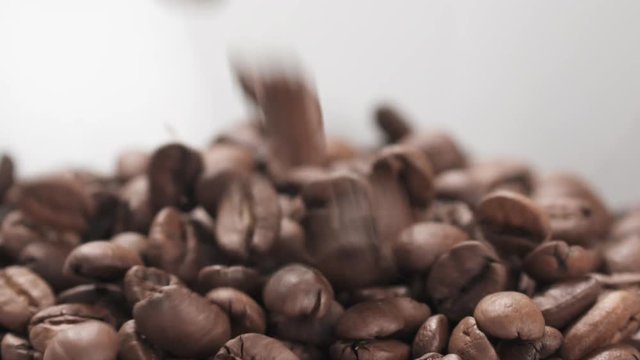 Slow motion closeup coffee beans falling into bowl