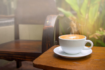 Selective focus with Hot coffee latte art heart shape in white cup on wooden table with blur of...