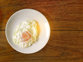 Fires egg with white plate on wooden background in the morning time.