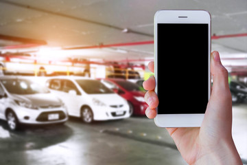 Man hands holding mobile smart phone in indoor car parking...