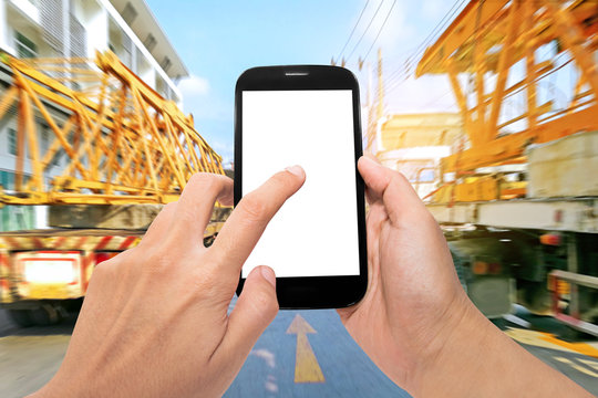 Hand holding smartphone and internet of things technology with trucks on the road and sunshine background.