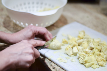 Hands cutting canned artichokes