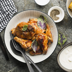 Appetizing chicken pieces in a hot sweet frosting baked in the oven in a baked pumpkin, sour cream and basil in a serving plate on a dark background. Top View.