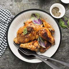 Appetizing chicken pieces in a hot sweet frosting baked in the oven in a baked pumpkin, sour cream and basil in a serving plate on a dark background. Top View.