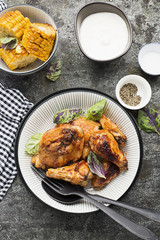 Appetizing chicken pieces in a hot sweet frosting baked in the oven in a baked pumpkin, sour cream and basil in a serving plate on a dark background. Top View.