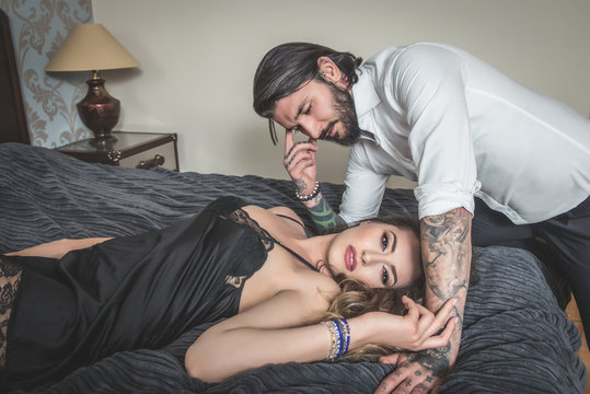 Tattooed Man Reaching For A Sensual Woman In Bed, Boudoir Couple