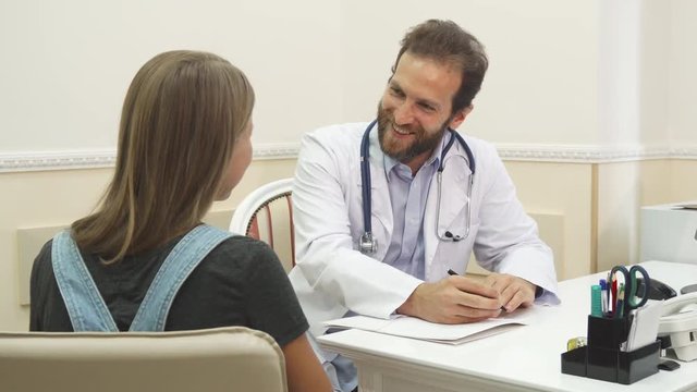 The doctor gives recommendation to the patient. He is telling a joke and they are both laughing. The girl comes to the therapist. They are sitting in doctors office